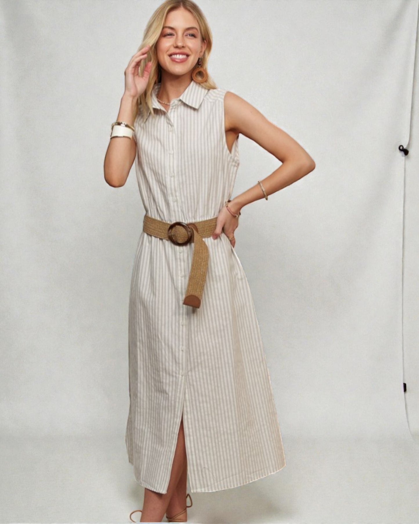 Woman wearing a beige striped dress with a belt on a plain background