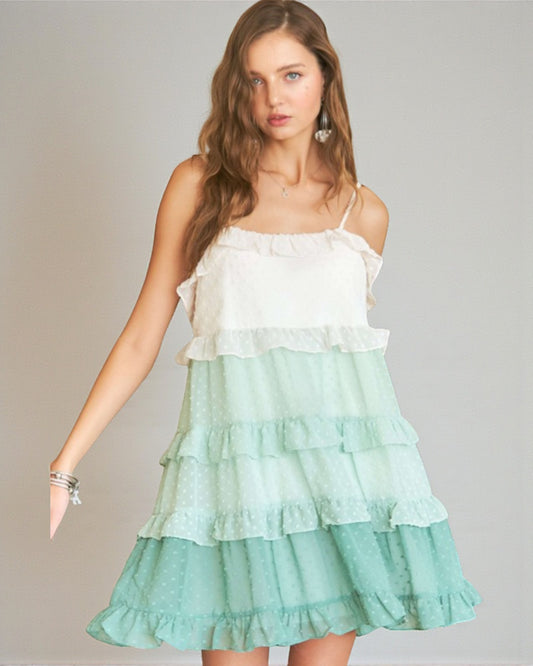 Woman wearing a white top and green tiered skirt against a gray background