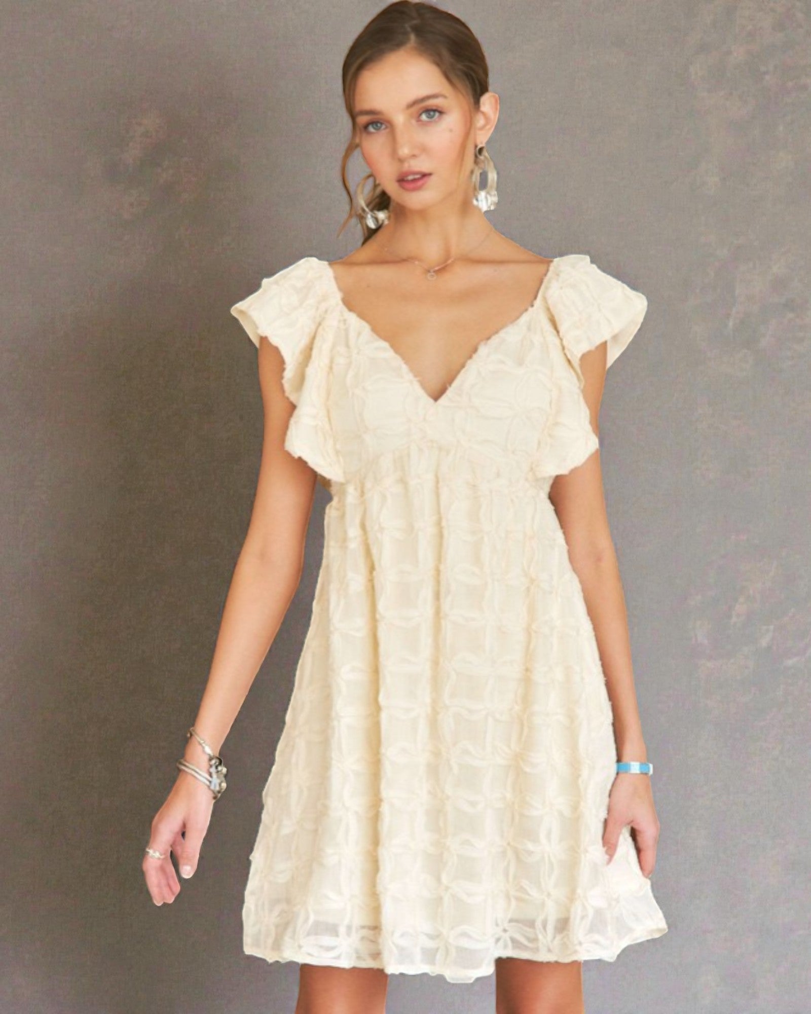 Woman wearing a cream-colored dress against a gray background