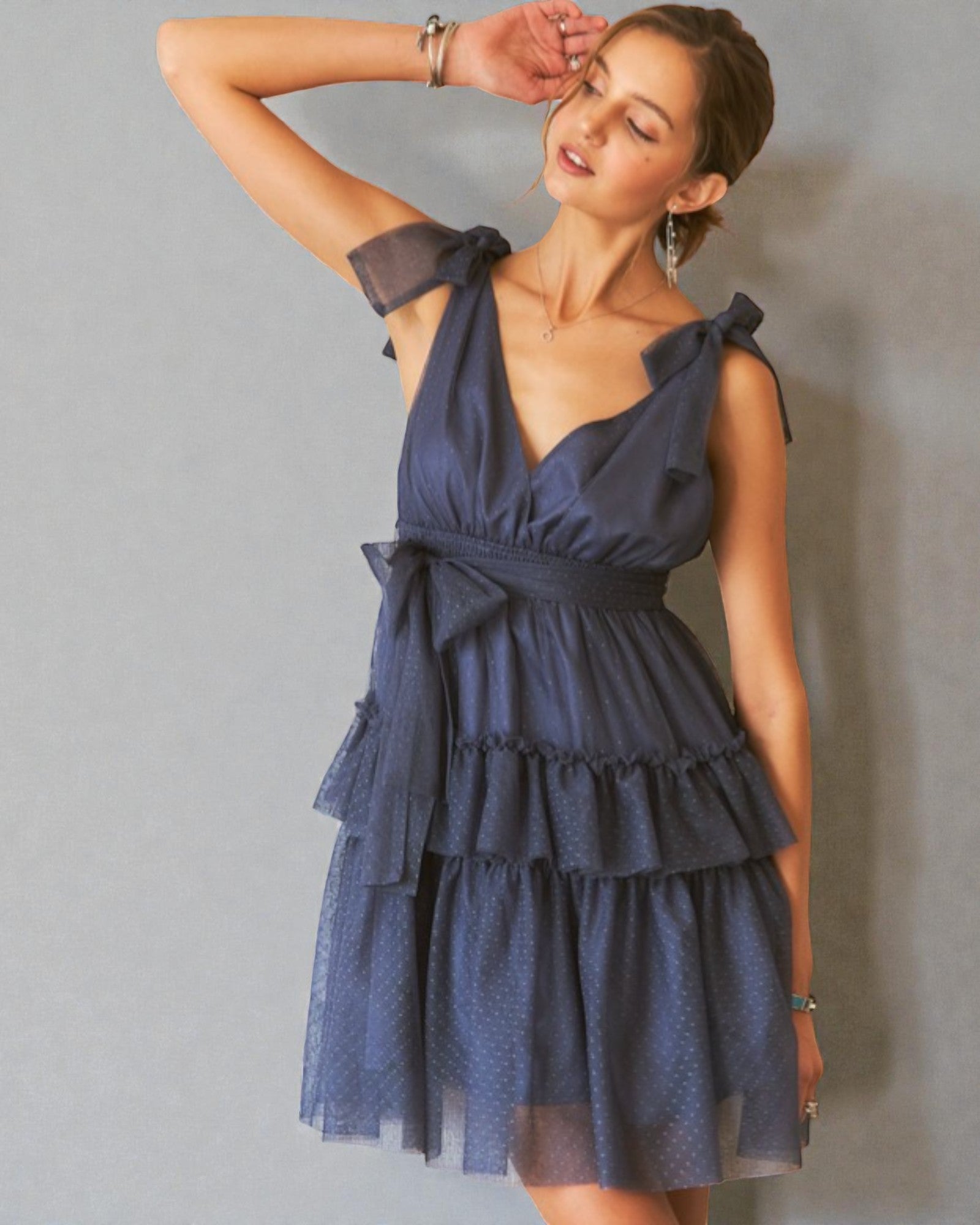 Woman wearing a blue dress with ruffled layers against a gray background