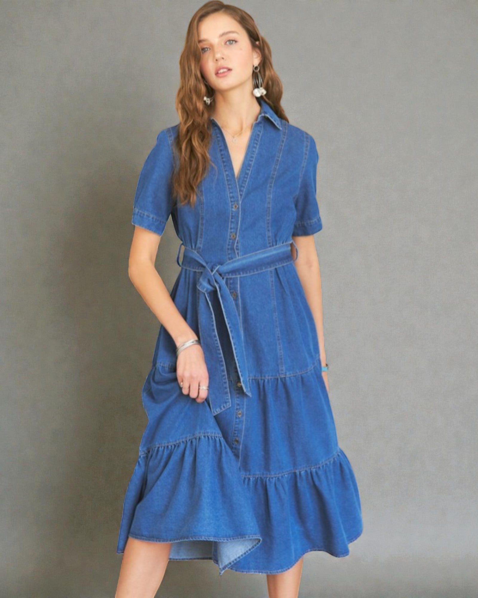 Woman wearing a blue denim dress against a gray background