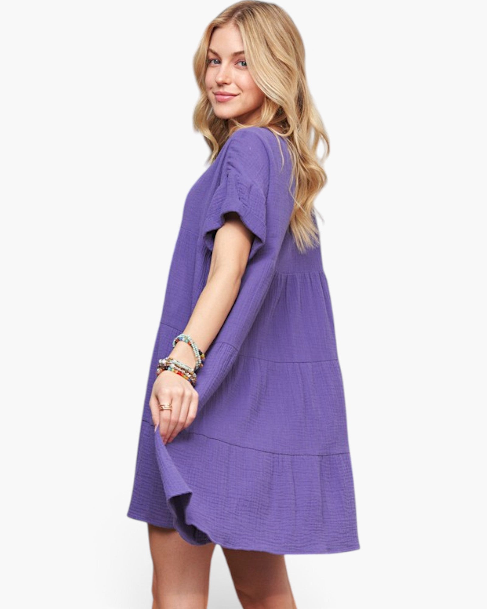 A woman modeling a short-sleeve purple textured dress against a plain white background.