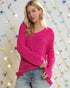Woman wearing a bright pink sweater with a colorful string light background