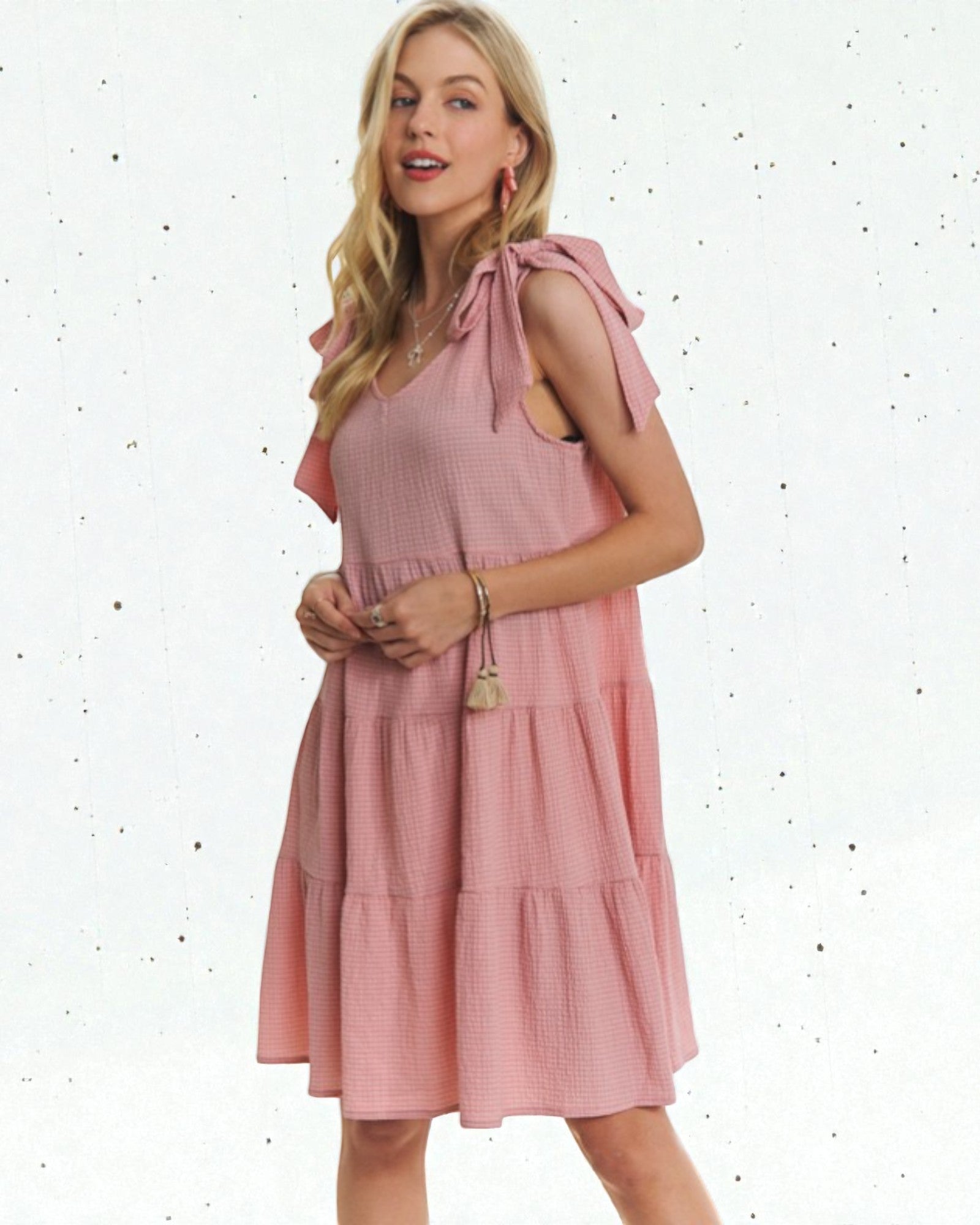 Woman wearing a pink dress with ruffled sleeves on a white background