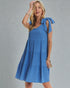 Woman wearing a blue dress with bow sleeves against a gray background