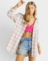 Woman wearing a plaid shirt over a pink crop top and denim shorts on a white background