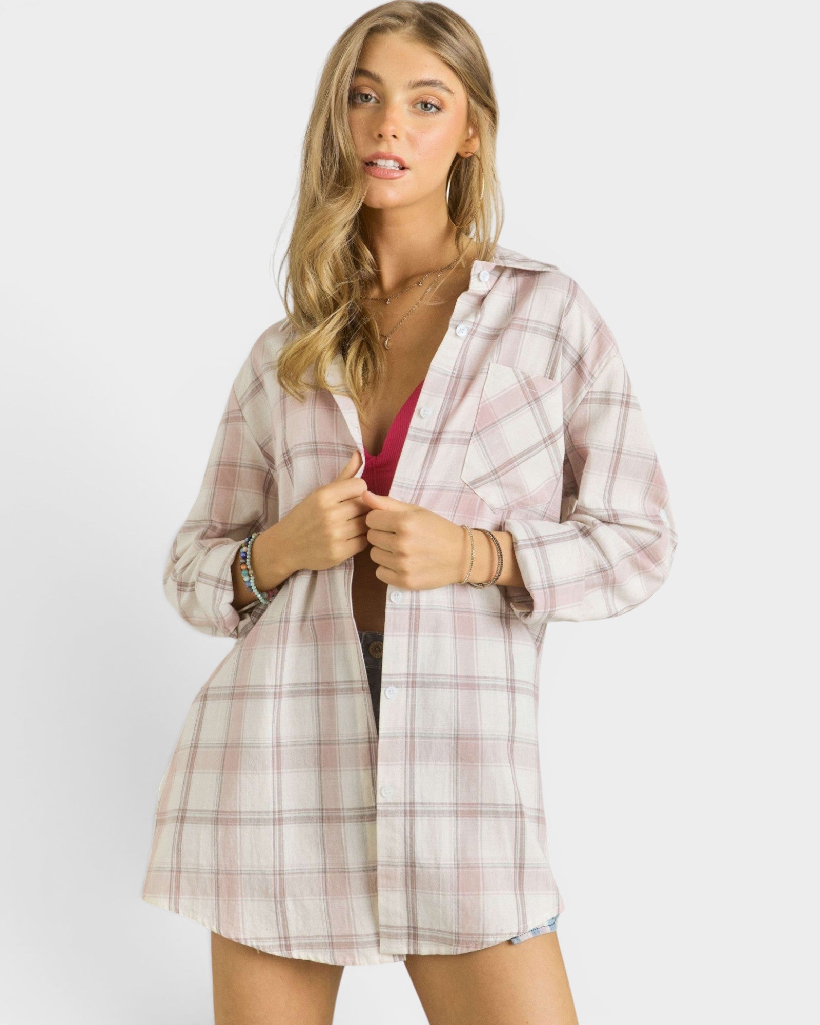 Woman wearing a plaid shirt over a pink top on a white background