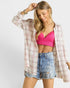 Woman wearing a pink crop top, plaid shirt, and denim shorts on a white background
