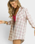 Woman wearing a plaid shirt over a pink top on a white background