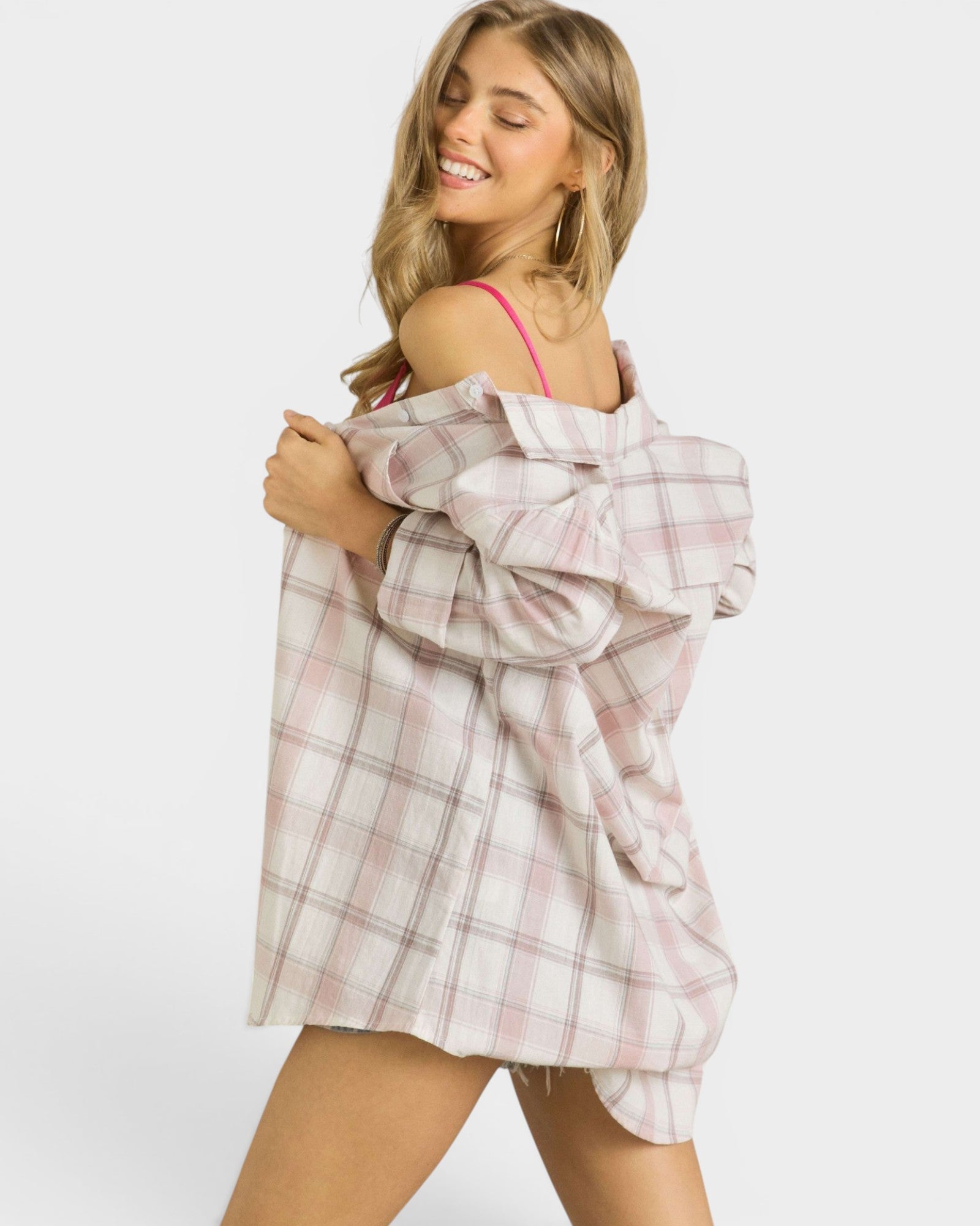 Woman holding a plaid shirt over her shoulder against a white background