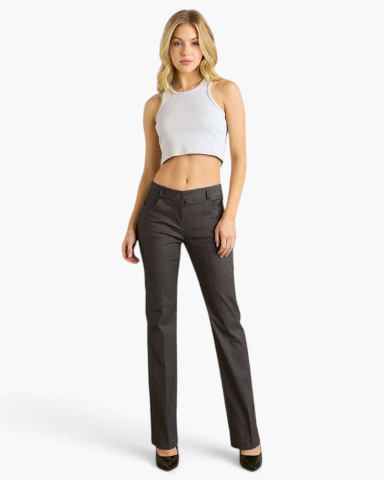 A woman modeling a pair of dark charcoal gray straight-leg pants with a white ribbed crop top, standing against a plain white studio background.