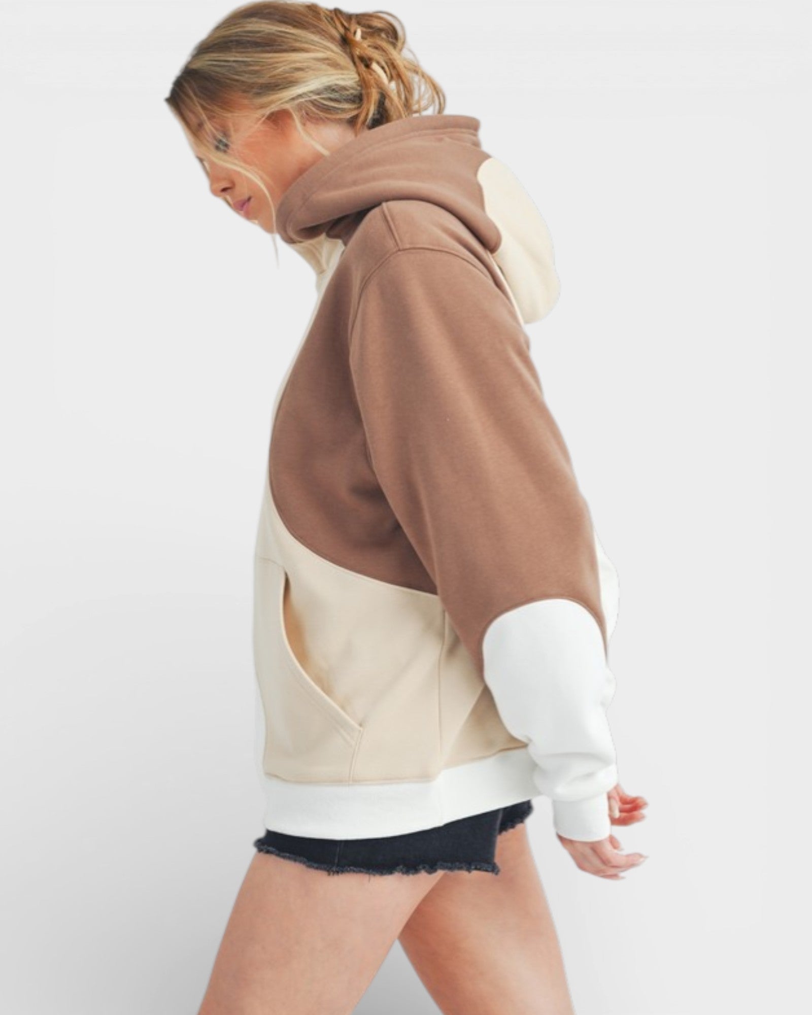 Person wearing a brown and beige color-blocked hoodie on a white background