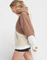 Person wearing a brown and beige color-blocked hoodie on a white background