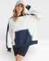 Woman wearing a white and navy oversized sweater with black shorts on a white background