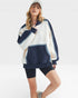 Woman wearing a navy and white striped hoodie with black shorts on a white background