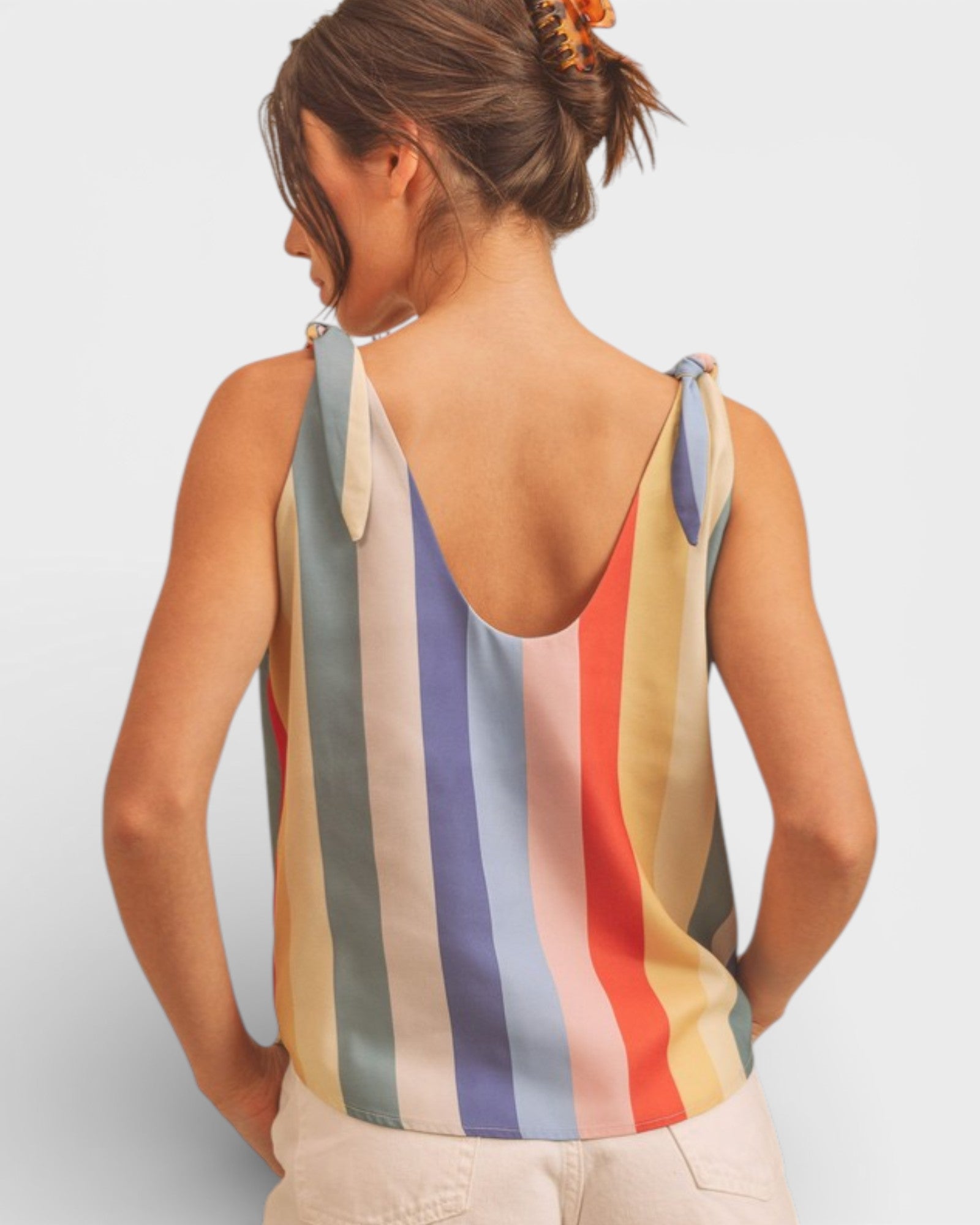 Woman wearing a multicolored striped tank top against a plain background