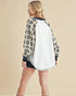 Person wearing a leopard print and white baseball jacket on a beige background