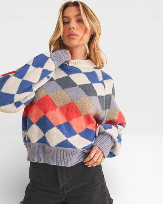 Woman wearing a colorful diamond pattern sweater against a white background