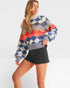 Woman wearing a colorful checkered sweater and black shorts on a white background