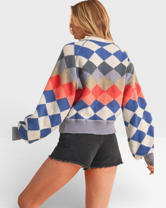 Person wearing a colorful diamond pattern sweater on a white background