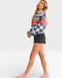 Woman wearing a colorful checkered sweater and denim shorts on a white background