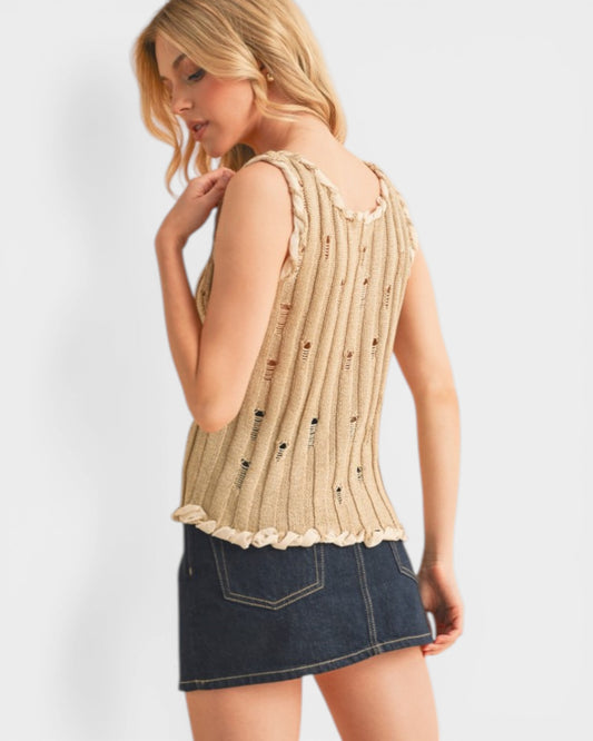 Woman wearing a beige sleeveless top and denim skirt on a white background