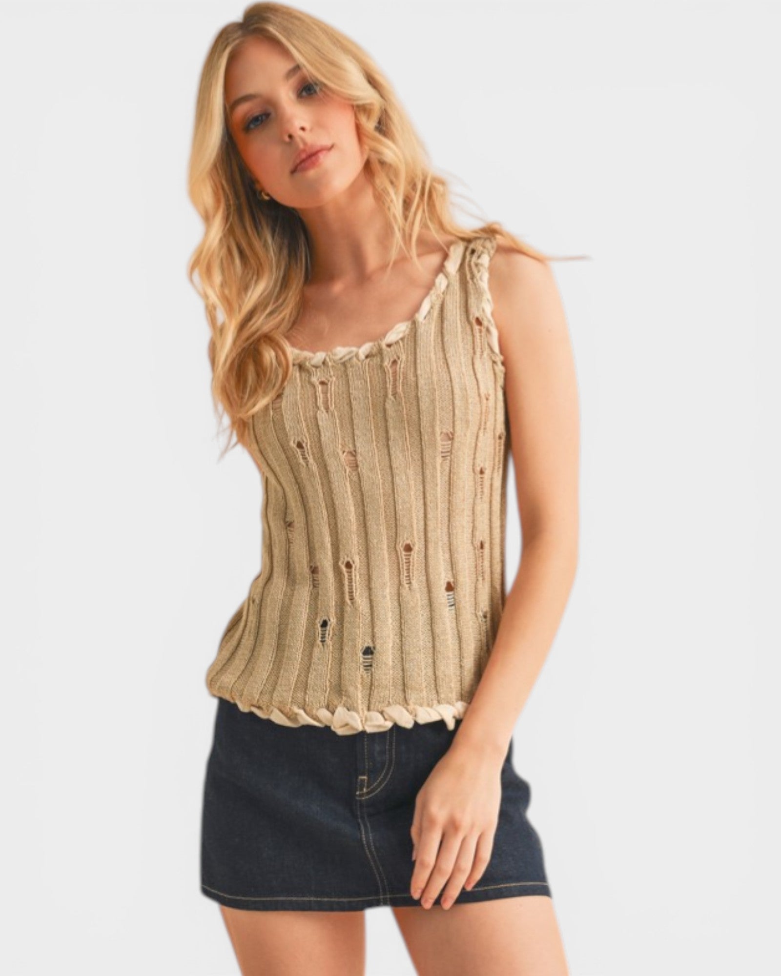 Woman wearing a beige ribbed tank top and denim skirt on a white background