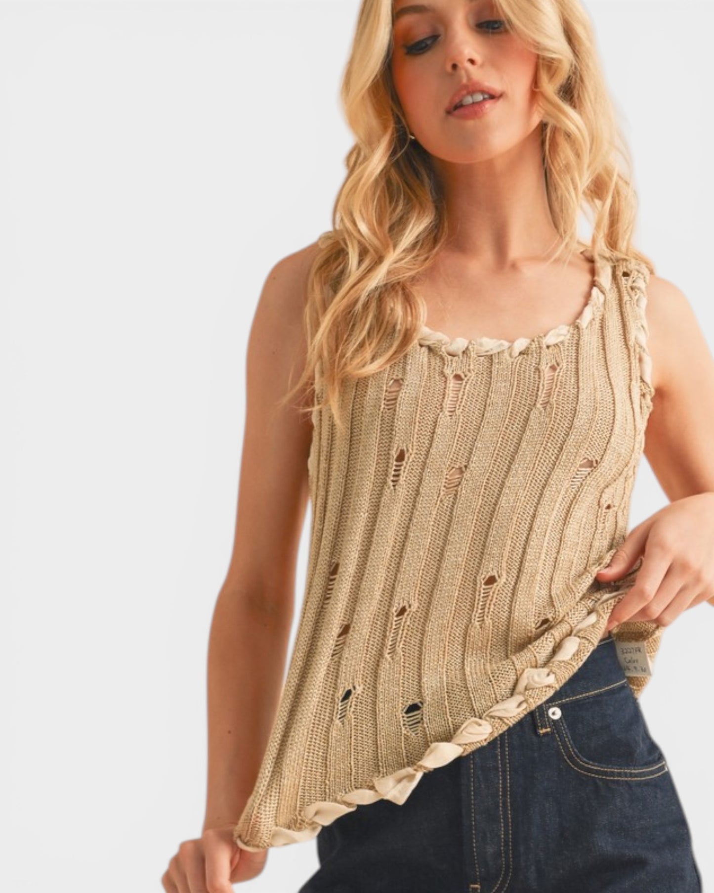 Woman wearing a beige knitted tank top with a white background