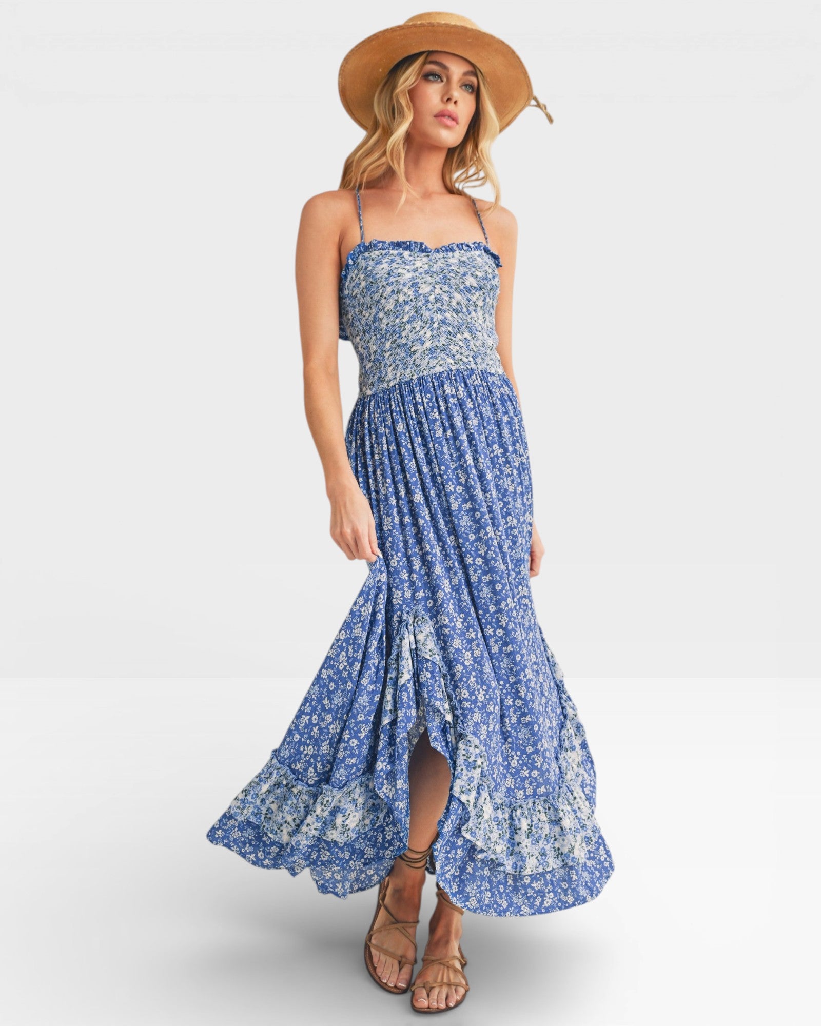Woman wearing a blue floral dress and straw hat on a white background
