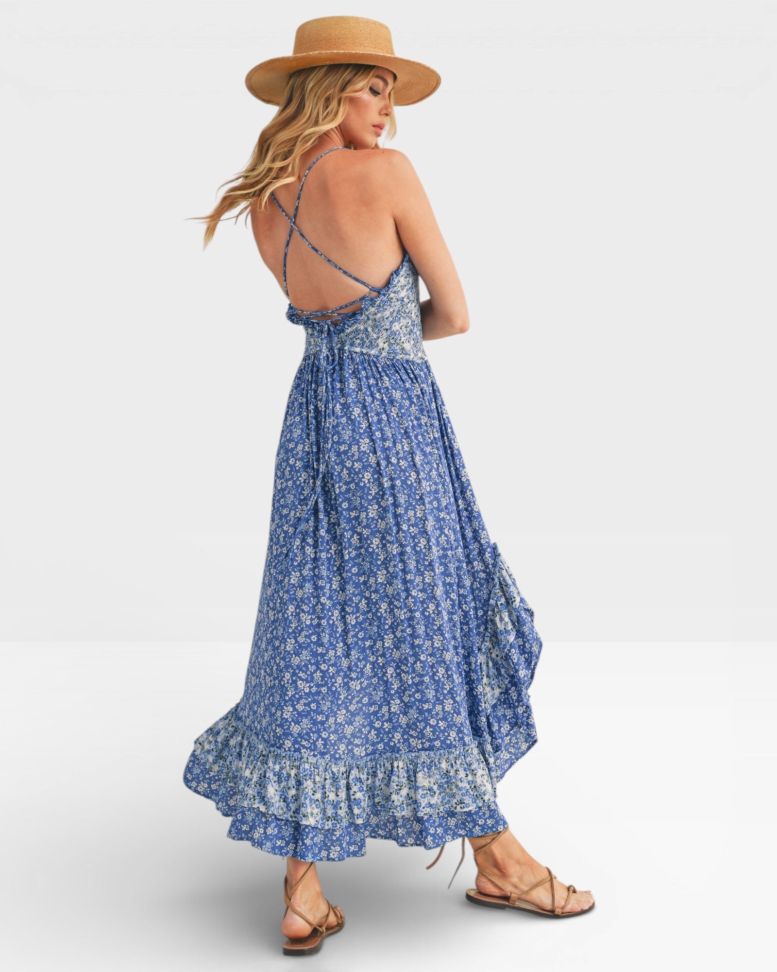 Woman wearing a blue floral dress and tan hat on a white background