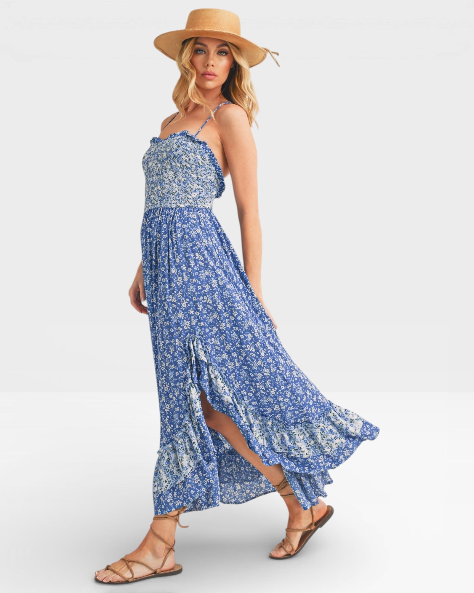 Woman wearing a blue floral dress and straw hat on a white background
