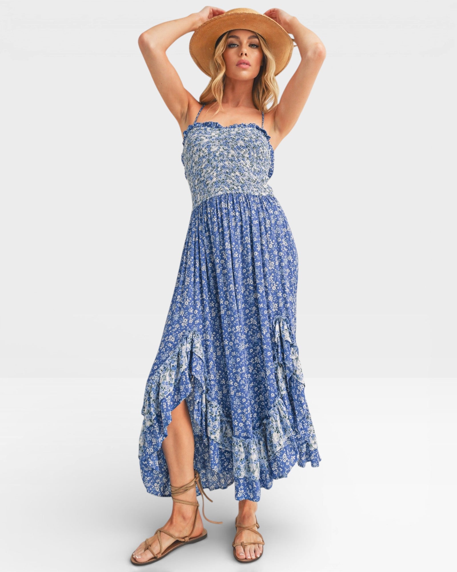 Woman wearing a blue floral dress and straw hat on a white background