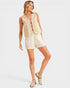Woman wearing a beige sleeveless top and shorts on a white background