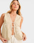 Woman wearing a beige sleeveless top with white embroidery on a light gray background