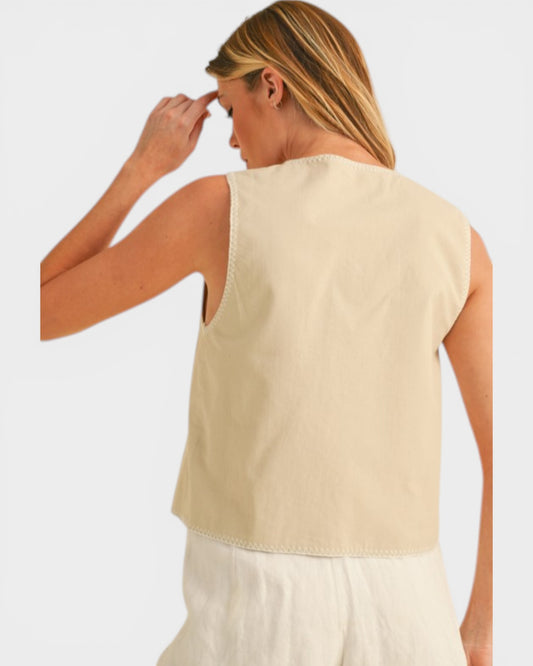 Woman wearing a beige sleeveless top against a white background
