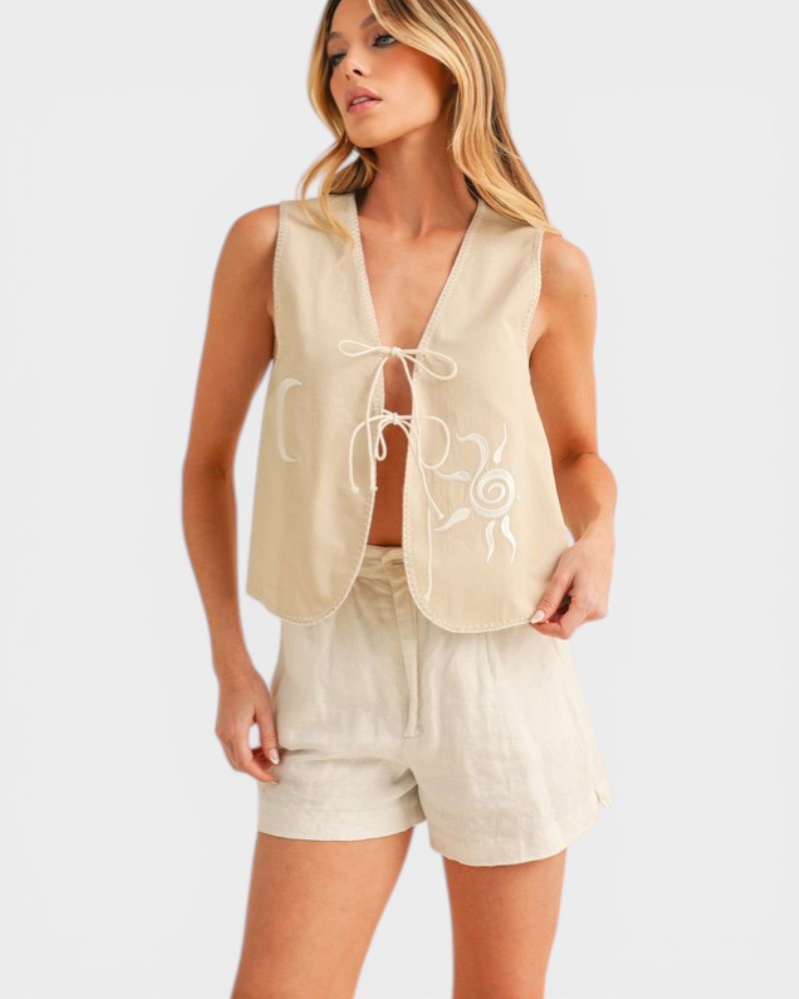 Woman wearing a beige sleeveless top and shorts set on a white background