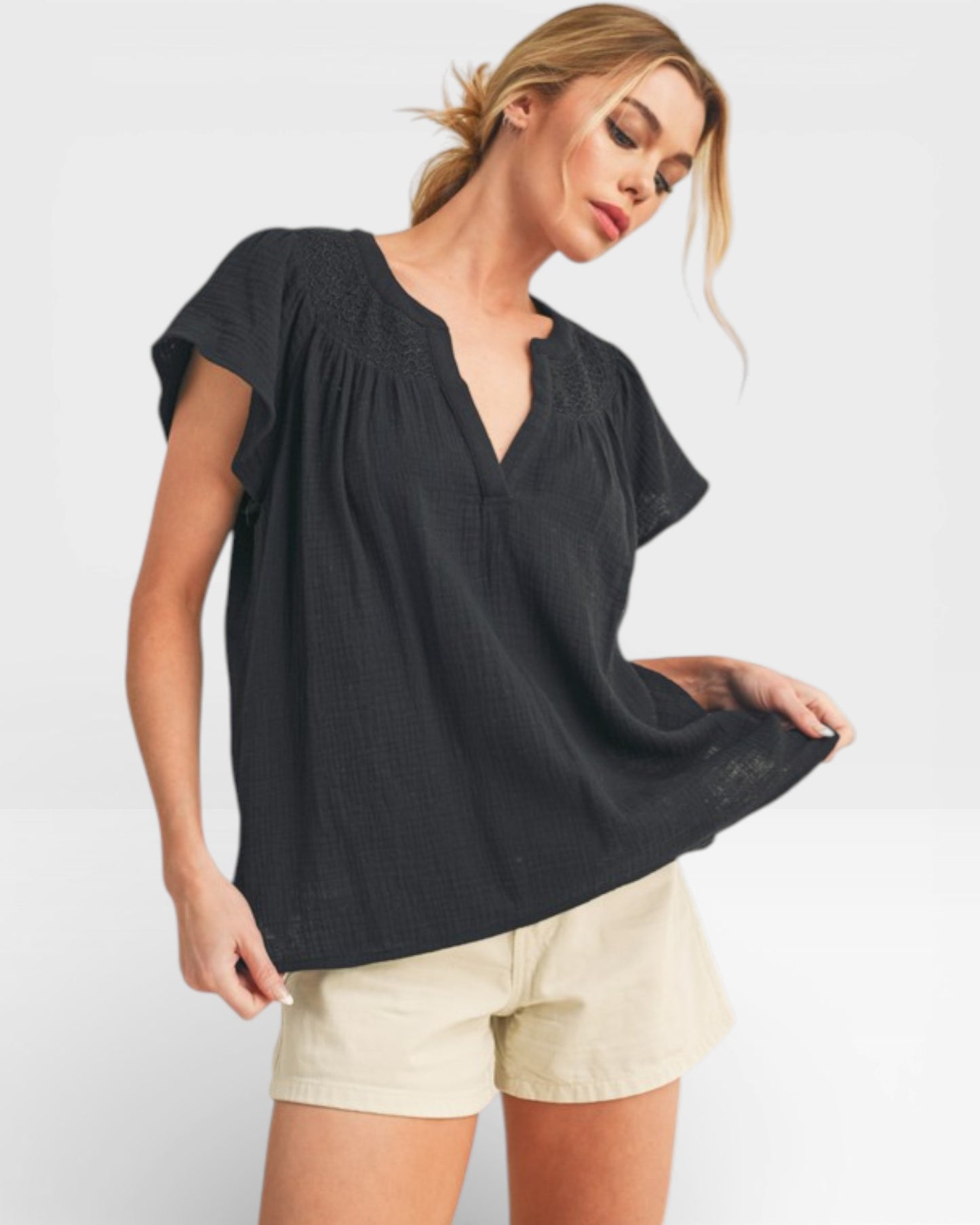 Woman wearing a black top and beige shorts on a white background