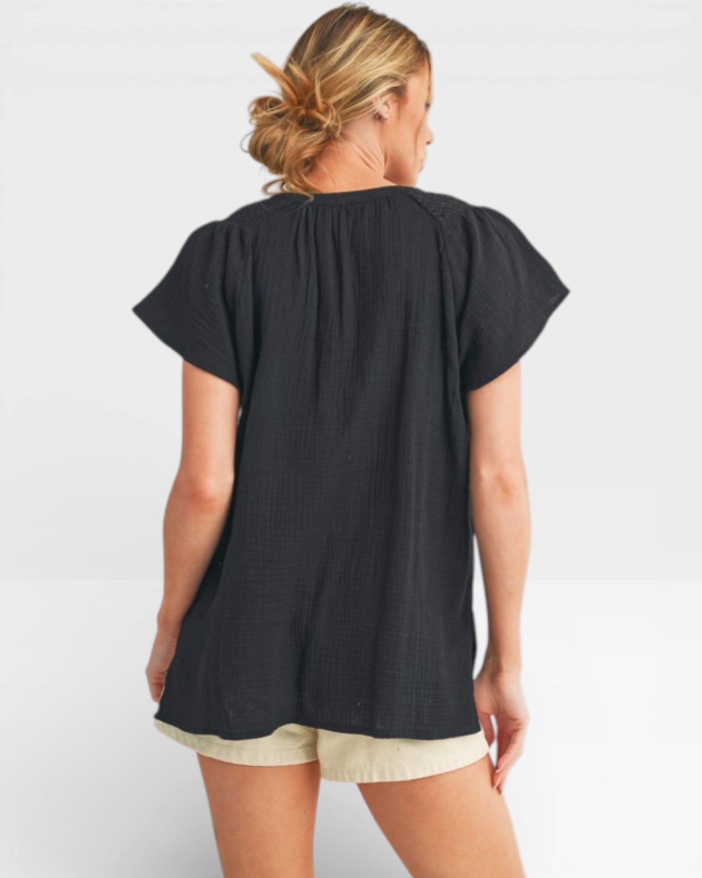 Woman wearing a black top and beige shorts on a white background