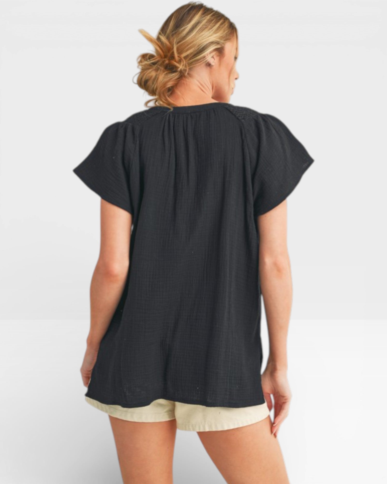 Woman wearing a black top and beige shorts on a white background