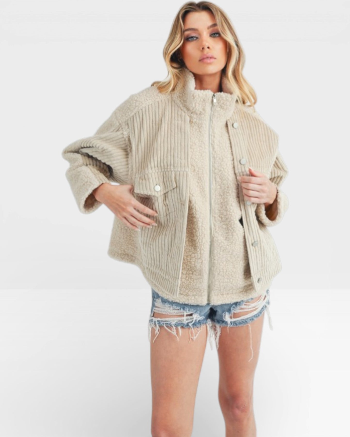 Woman wearing a beige corduroy jacket and denim shorts on a white background