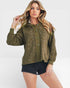 Woman wearing a green patterned shirt and black shorts on a white background