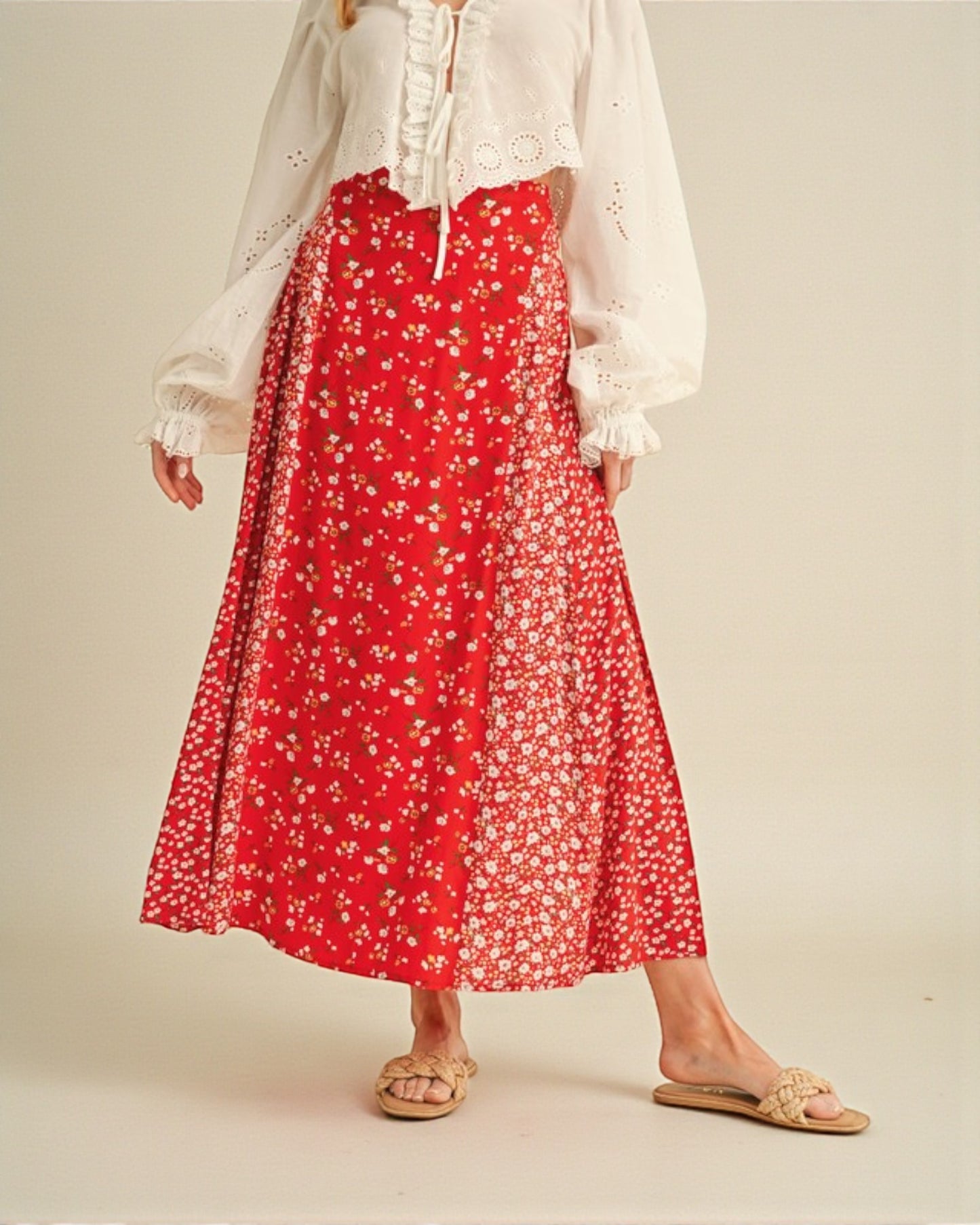 Person wearing a white blouse and red floral skirt on a beige background