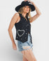 Woman wearing a black sleeveless top with a heart design and denim shorts on a white background