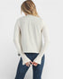 Woman wearing a cream-colored long-sleeve top with bell sleeves on a white background