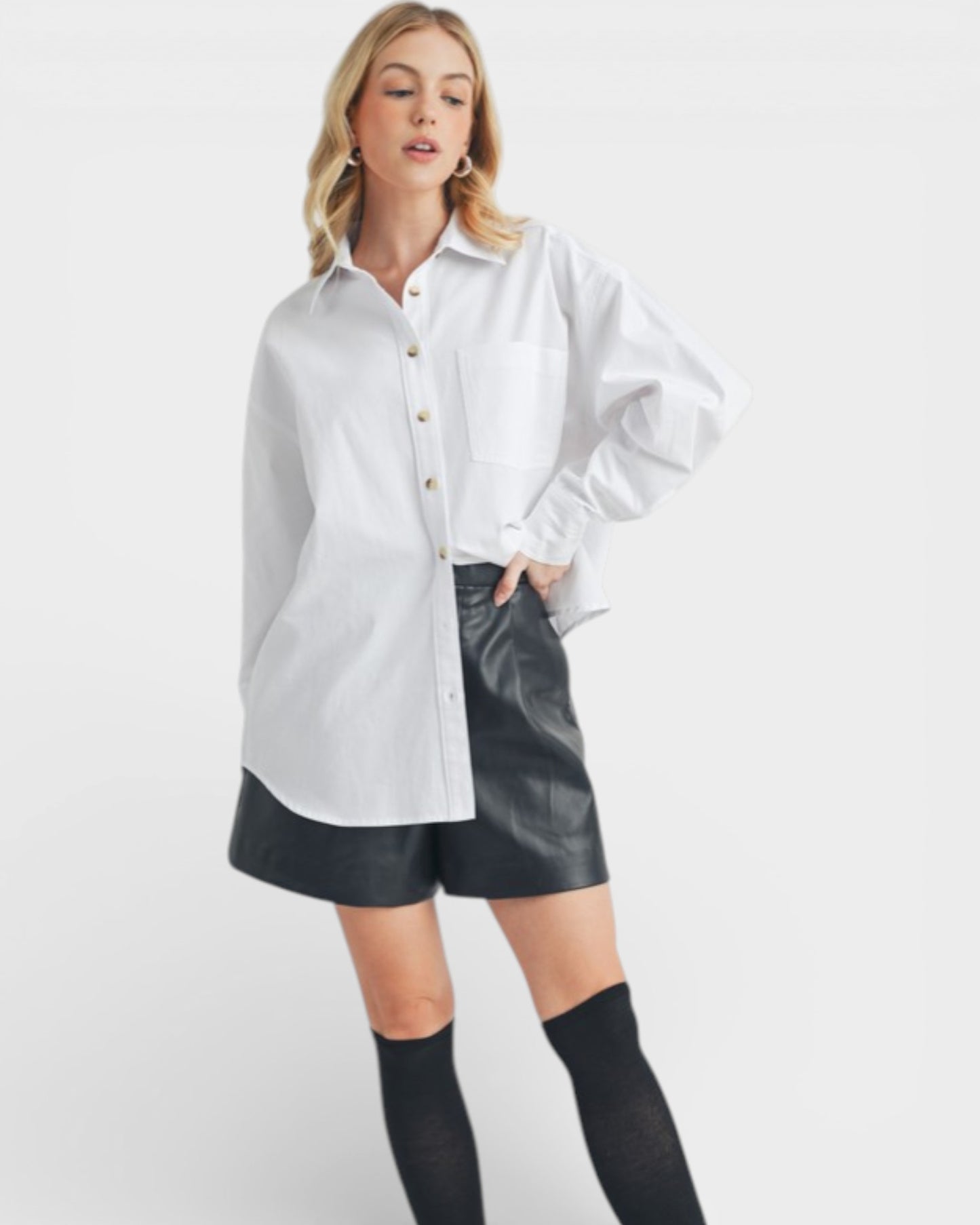 Woman wearing a white shirt and black leather shorts on a white background