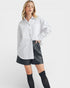 Woman wearing a white shirt and black leather shorts on a white background