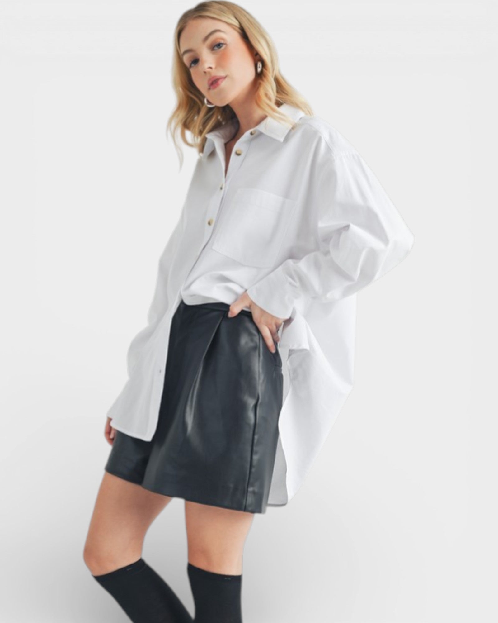Woman wearing a white oversized shirt and black leather skirt on a white background