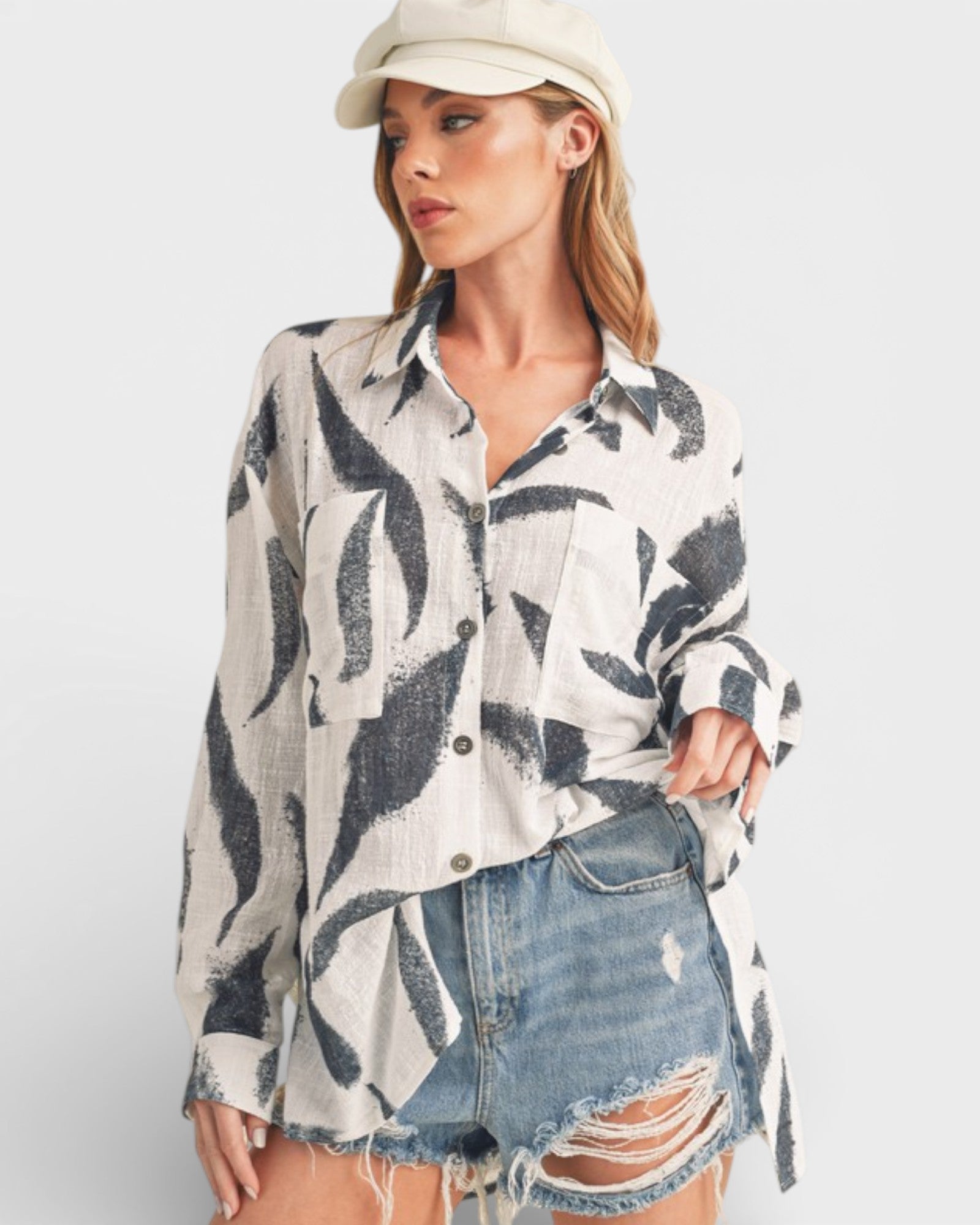 Woman wearing a patterned shirt and denim shorts on a white background