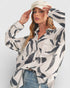 Woman wearing a patterned shirt and cap against a white background