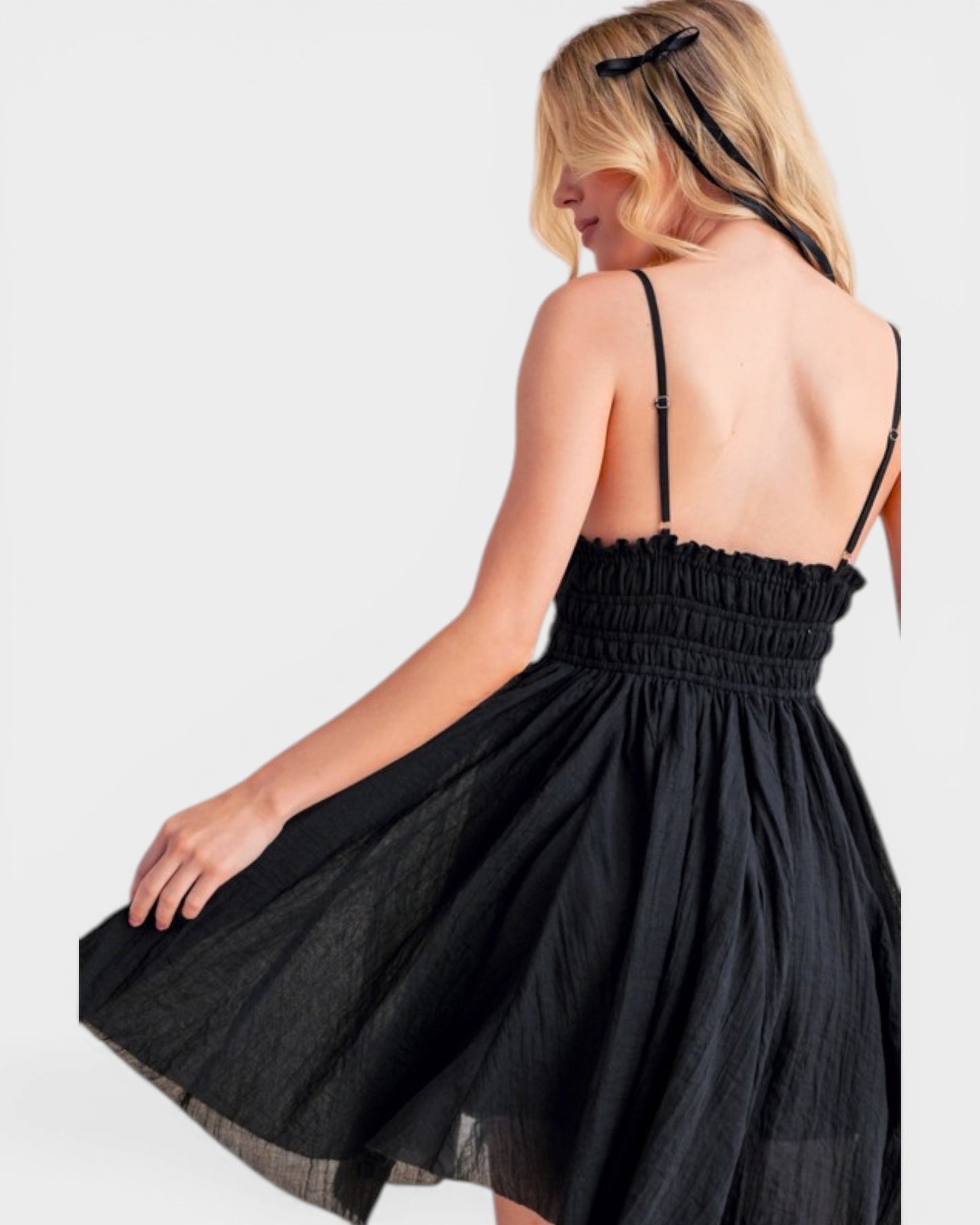 Woman wearing a black dress with thin straps on a white background